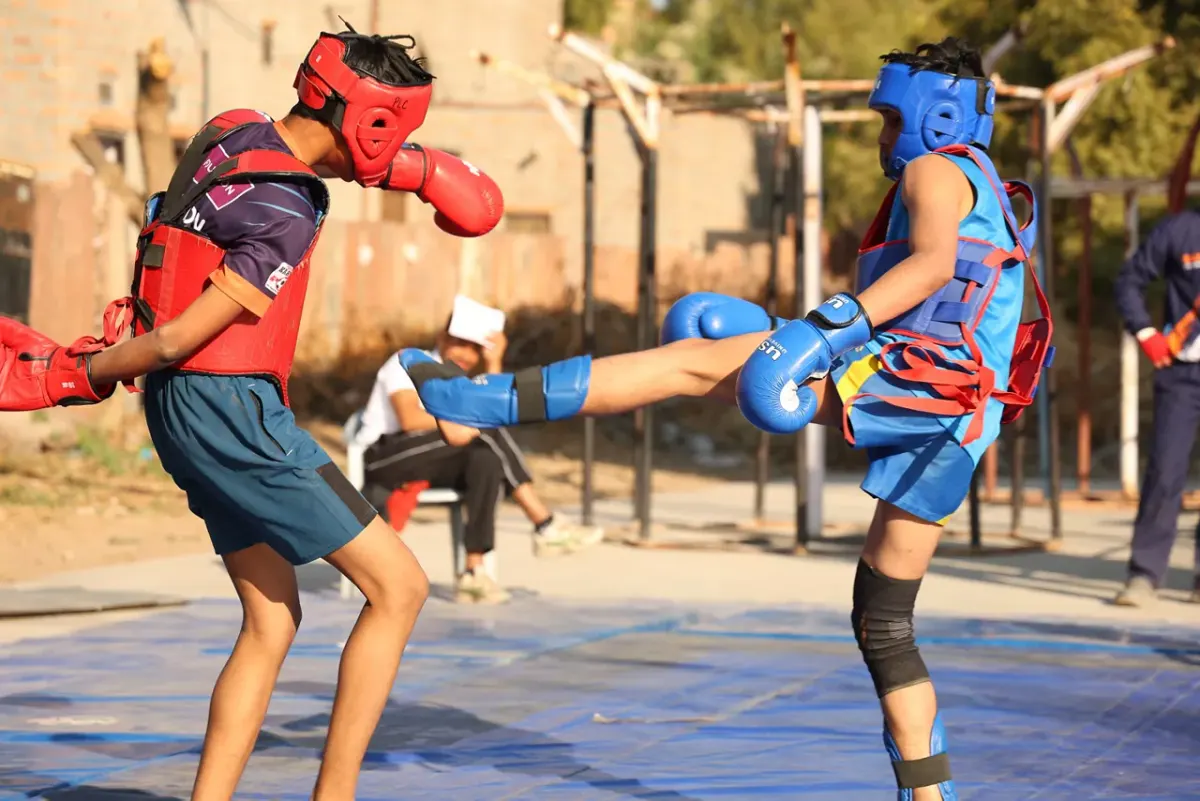 Two young athletes sparring at an outdoor training ground